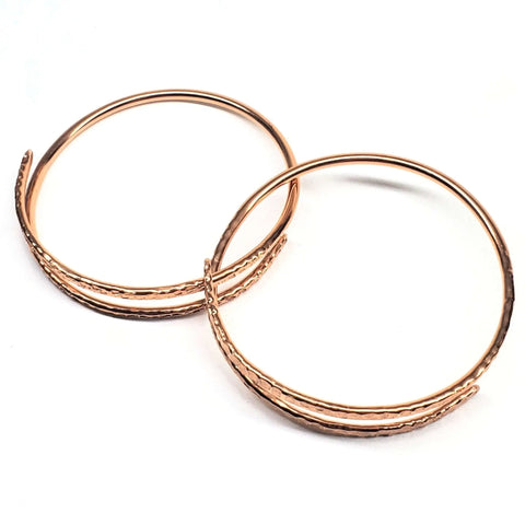 The Alexa Martha Designs 2 Piece Handmade Interlocking Full Overlap Copper Bangle Set features two overlapping copper bangles with a wavy textured design, displayed on a white background.
