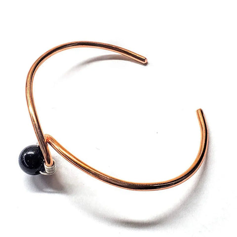 The Handmade Copper Silver Ribbon Child Abuse Awareness Teardrop Bangle by Alexa Martha Designs is a minimalist open copper bracelet with silver wire wrapping, showcased on a white background.