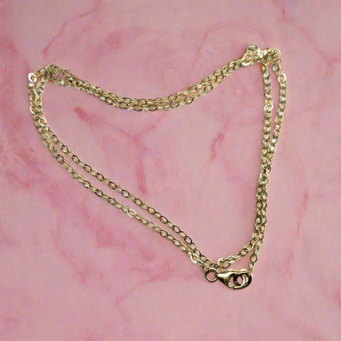 The Super Sparkly Crystal Pillar Pendant in Green Blue and Rose by Alexa Martha Designs, shown with an optional necklace, is displayed in a loose oval shape on a pink marbled background.