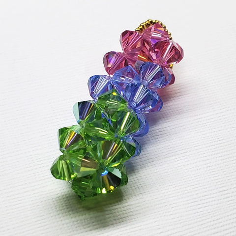 The Super Sparkly Crystal Pillar Pendant by Alexa Martha Designs features green, blue, and rose faceted crystals, stacked vertically and shimmering like a beaded charm—available as a pendant or with an optional necklace.