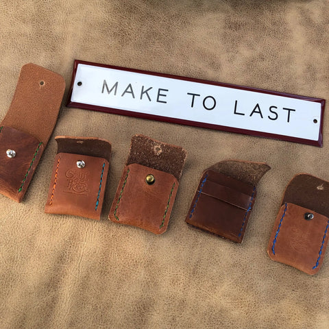 Five Sully + Proper Supply Coin Pouches with colorful stitching are displayed on tan leather. Above them, a white sign reads MAKE TO LAST. Handmade in the USA, these pouches are a perfect minimalist accessory.