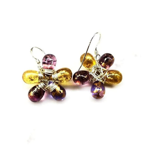 Alexa Martha Designs Purple and Yellow Flower Sterling Silver Earrings feature handmade floral designs with gold and purple Czech glass petals, delicately wrapped in silver wire and displayed on a white background.