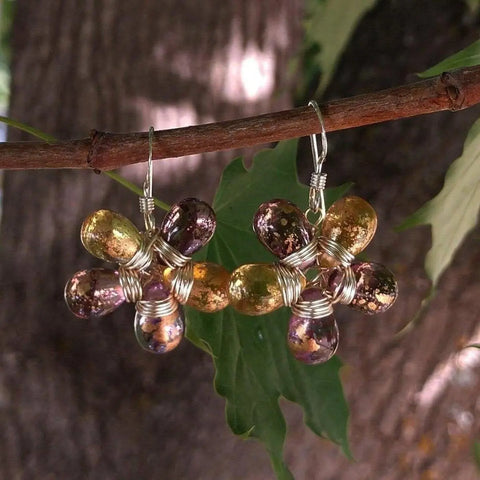 The Purple and Yellow Flower Sterling Silver Earrings by Alexa Martha Designs feature handmade teardrop Czech glass beads in gold and purple, arranged in a floral pattern with silver wire.
