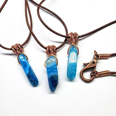 The Alexa Martha Designs Wire Wrapped Pointed Turquoise Agate Leather Necklace for Him and Her features blue agate pendants wrapped in copper wire on brown leather cords, finished with a handcrafted copper clasp and hook.