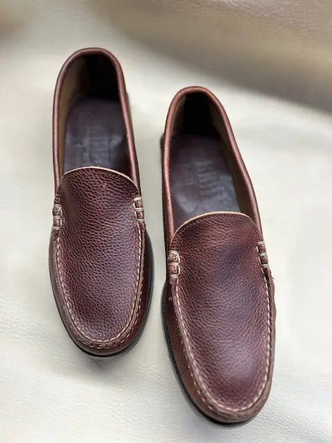 A pair of BBH Loafer shoes in brown, featuring handsewn visible stitching around the edges, displayed side by side on a light surface to highlight their classic American shoemaking heritage.