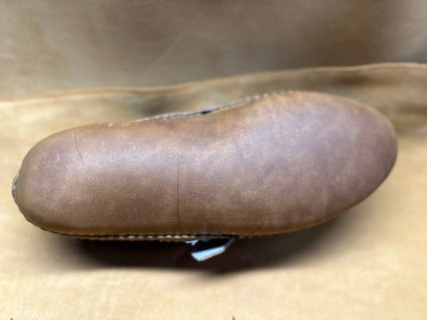 A close-up of the BBH Mica Mocc sole displays its smooth, premium brown leather with subtle creases and edge stitching, set against a matching brown background.