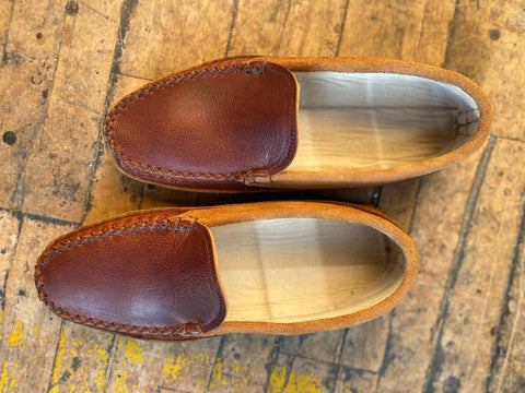 The BBH ‘Northeaster’ moccasin loafers, crafted from brown leather with tan suede sides and handsewn for quality American craftsmanship, are shown side by side on a vintage wooden floor.