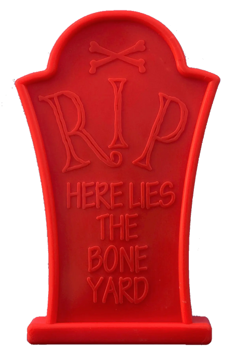 The Headstone Ultra Durable Nylon Dog Chew Toy by SodaPup is a red plastic gravestone with RIP Here Lies The Bone Yard and crossed bones at the top, made for aggressive chewers.