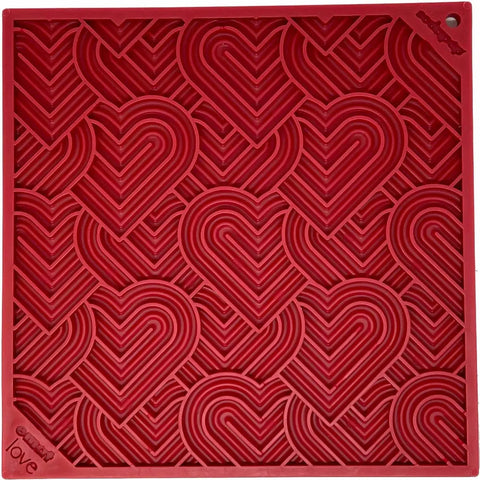 The SodaPup Heart Design Love EMat Lick Mat is a red silicone mat with embossed overlapping hearts in a geometric pattern and small decorative text and symbols on the corners, perfect for dog enrichment and pet treats.