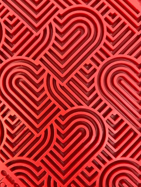Close-up of a red Heart Design Love EMat Lick Mat by SodaPup, featuring a textured surface with repeating geometric heart patterns to engage dogs and provide enrichment.