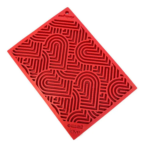 The Heart Design Love EMat Lick Mat by SodaPup is a red silicone dog enrichment toy with a raised pattern of hearts and maze lines, featuring embed and love embossed near the bottom.