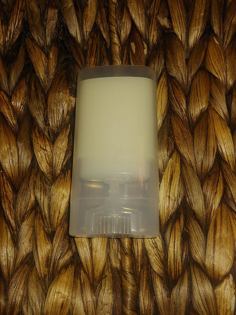 The Bathsheba Body Works Moisture Bar - Love Me is a clear plastic deodorant stick with solid white product, shown on a brown woven surface—ideal for nourishing mature skin.