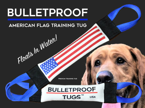 A tan dog eyes two Patriotic Fire Hose Training Tugs with blue handles in American flag colors. Text: BULLETPROOF Pet Products Inc, Flag Series. Floats in water! Durable premium fire hose dog toy—BULLETPROOF TUGS™ USA.