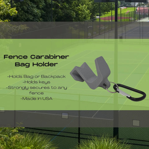 A Chatelet Manufacturing Carabiner Fence Holder bag in gray is shown with a black carabiner attached. Its made in the USA, holds bags or keys, secures to fences, and is pictured with a tennis court behind the fence.
