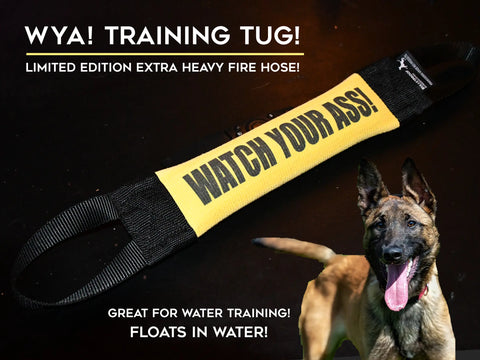 The Watch Your Ass Fire Hose Training Tug by Bulletproof Pet Products Inc, shown in yellow with black handles, is a USA-made, durable, water-friendly dog training toy displayed next to a happy dog on a dark surface.