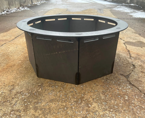 A round, black Heavy Gauge Fire Ring by Ohio Flame (made in USA) sits on textured outdoor concrete with snow along the pavement edges.