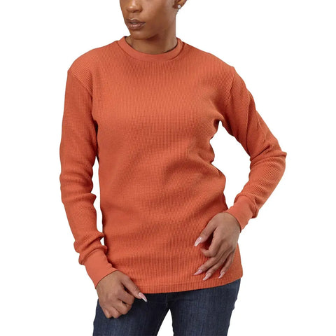 A person in dark jeans wears a textured orange Spiritex | Sustainable Apparel Long Sleeve Crewneck Heavy Thermal, standing with one hand on their hip and the other by their thigh, head turned slightly to the side.