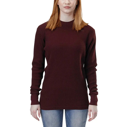 A woman with straight, shoulder-length reddish-brown hair wears a maroon Spiritex Long Sleeve Crewneck Heavy Thermal and light blue jeans, standing against a white background. Her face is partially visible.
