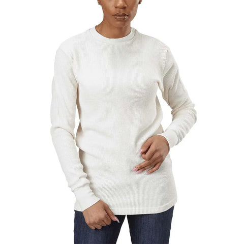 A person wears the Spiritex | Sustainable Apparel Long Sleeve Crewneck Heavy Thermal in off-white with dark blue jeans, standing against a plain white background. Only their upper body is visible, one hand near the waist.