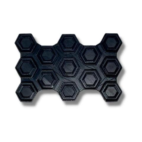 The Chatelet Manufacturing Snowboard Stomp Pad - Hexagon Pattern is a black, rectangular traction pad with raised hexagons in rows and an irregular border, designed for superior grip and weatherproof adhesion on snowboards.