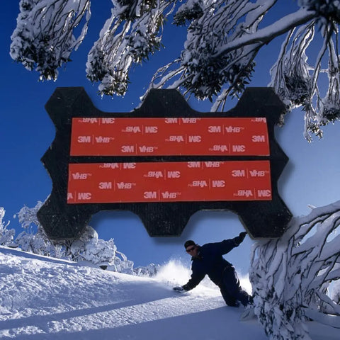 A snowboarder rides down a snowy slope with tree-lined edges; in front, a Chatelet Manufacturing Snowboard Stomp Pad - Hexagon Pattern shows specialized grip and weatherproof 3M VHB adhesion for reliable performance.