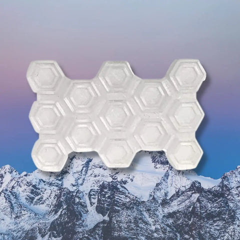 The Chatelet Manufacturing Snowboard Stomp Pad - Hexagon Pattern, designed for better grip and adhesion to snowboards, is displayed centered over snowy mountains with a pastel sky backdrop.