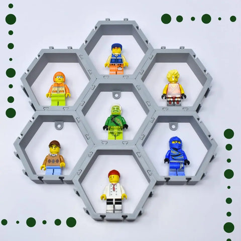 Display up to seven LEGO minifigures in the Chatelet Manufacturing Hexagon Wall Display—interlocking hex blocks with green dotted corner designs on white, perfect for customizing and mounting your figures on the wall. Made in USA.