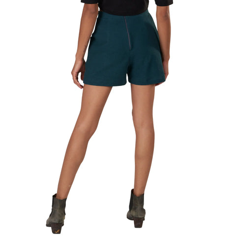 A person stands facing away in a black top, Spiritex | Sustainable Apparels Betty Hi Waist Shorts in dark green, and gray heeled ankle boots. Their legs are slightly apart with one knee bent against a plain white background.