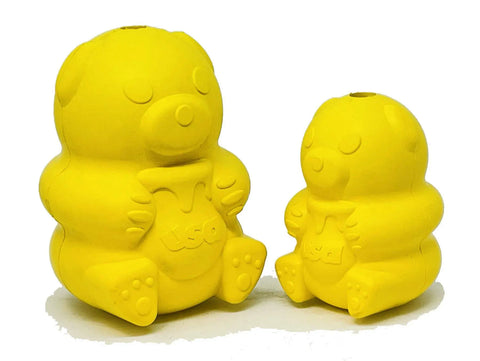 Two yellow Honey Bear EDispenser toys by SodaPup, one large and one small, sit side by side on a white background. Made from durable natural rubber, these treat dispensers for dogs each hold a USA-labeled jar and feature simple bear faces.