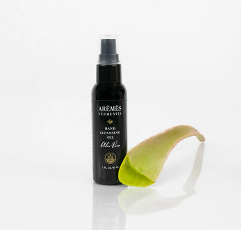 A black AREMES FERMENTIS Aloe Vera Hand Cleansing Gel stands upright beside a fresh aloe vera leaf on a white surface, providing effective sanitization with every use.