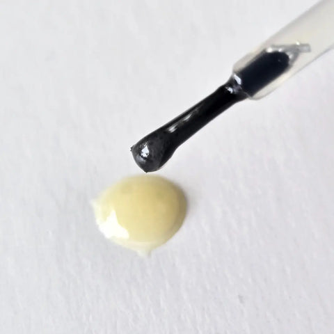 A close-up of Naturally London Hydrating Cuticle Oil (9mL) on a nail polish brush, with a drop on a white surface below—ideal for highlighting essential nail care and hydration.