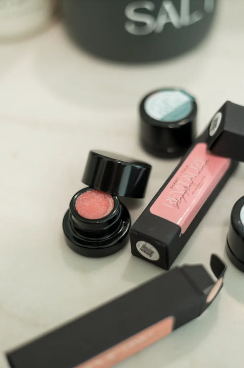 A small opened jar of Shanti + Tula Hydrating Natural Lip Balm sits beside its box and a closed jar on a light surface, highlighting this USA-made, non-greasy, lightweight moisture stick’s intense hydration.