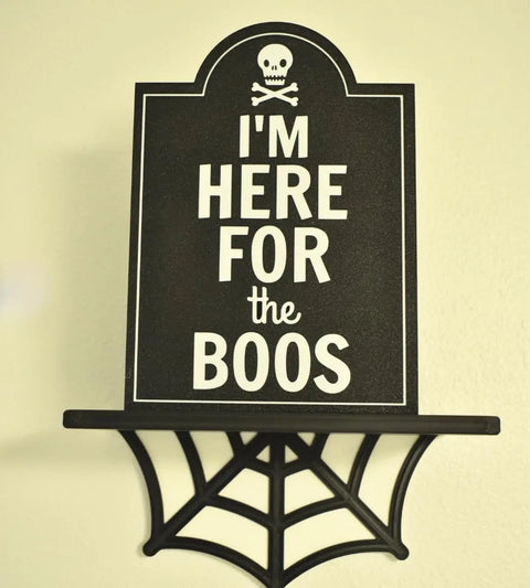 The Chatelet Manufacturing Im Here for the Boos Halloween Bar Sign Decor features a black tombstone-shaped sign with a skull and crossbones, perfect as a spooky Halloween party decoration. Made in the USA.
