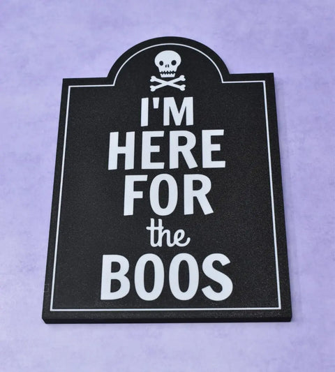 The Im Here for the Boos Halloween Bar Sign Decor by Chatelet Manufacturing features a tombstone shape with a skull and crossbones, perfect as a spooky Halloween party decoration for your bar or table. Made in the USA.