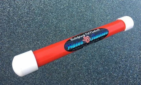 A red plastic tube with white caps, labeled Water Rattler by Bulletproof Pet Products Inc, rests on a glittery blue-gray surface—an interactive 12 floating fetch toy designed for water play with your dog.