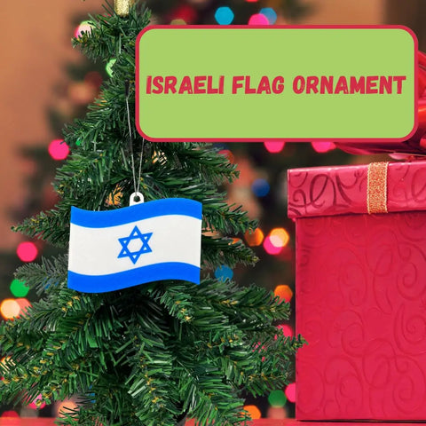 A small Christmas tree with a Chatelet Manufacturing Israeli Flag Christmas Ornament sits beside a large red gift box. Above, a bold sign reads ISRAELI FLAG ORNAMENT, showing festive support for Israel with this Made in USA ornament.