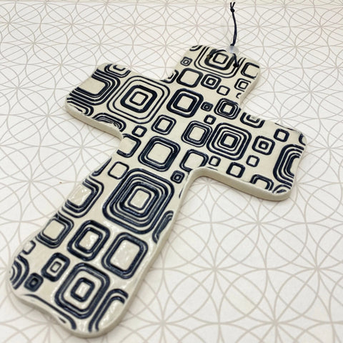 The Janecka JANECKA Cross of Hope, Black Square Pottery Wall Cross features a glossy ceramic finish with black geometric patterns and a hanging string, making it a unique housewarming gift.