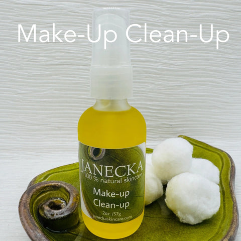 A small bottle of JANECKA Make-Up Clean-Up by Janecka Skincare rests on a green ceramic dish with three cotton balls, set against a light wood background. Large white text above reads Make-Up Clean-Up.