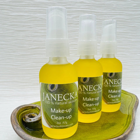 Three bottles of JANECKA Make-Up Clean-Up by Janecka Skincare, each 2oz/57g and labeled 100% natural skincare, sit on a green ceramic dish against a white textured background.
