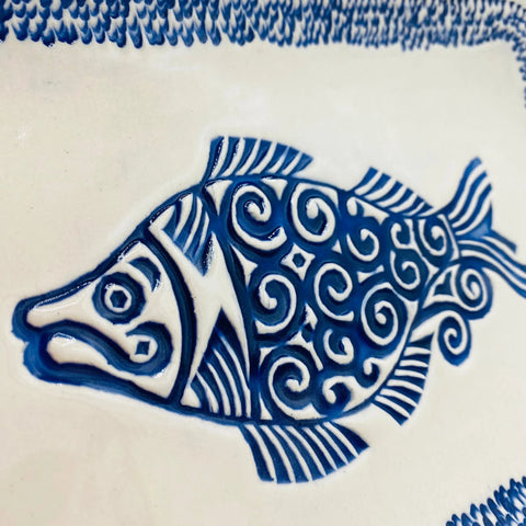 The JANECKA Blue Fish Tray by Janecka is a handmade pottery piece featuring intricate blue and white ceramic fish patterns and a decorative border—an ideal artisan gift crafted in traditional style.