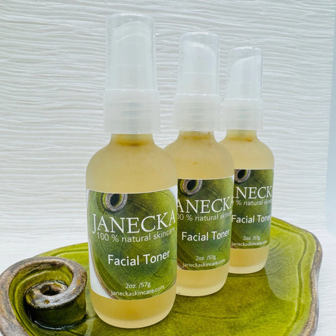 Three bottles of JANECKA Facial Toner by Janecka Skincare are arranged on a green ceramic tray with a spiral pattern, set against a textured white background.