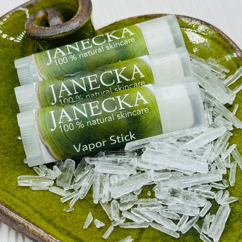 Three jars of JANECKA Herbal Vapor Rub by Janecka Skincare rest on a green ceramic dish, surrounded by translucent crystal shards, showcasing this organic congestion relief essential oils ointment.