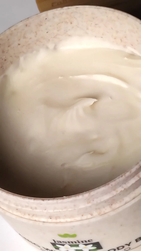 An open container of Forev'Herbs Jasmine Organic Whipped Body Butter displays its smooth, creamy white texture with a beautifully swirled surface.