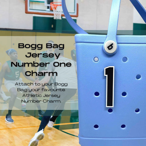 A close-up of a blue Bogg Bag features a black and white BOGLETS - Jersey Sports Uniform T-Shirt Number by Chatelet Manufacturing. Basketball players play in the gym background. Text reads: Jersey Number One Charm with instructions below.