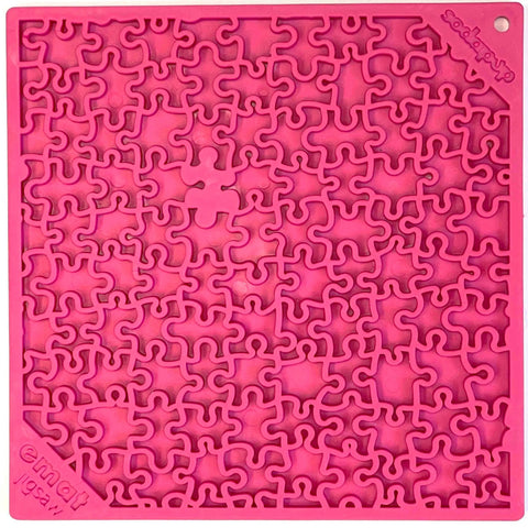 The Jigsaw Design EMat Enrichment Lick Mat by SodaPup is a square, pink silicone dog toy with a maze-like, interlocking pattern, embossed branding in two corners, and a small circular hole in one corner.