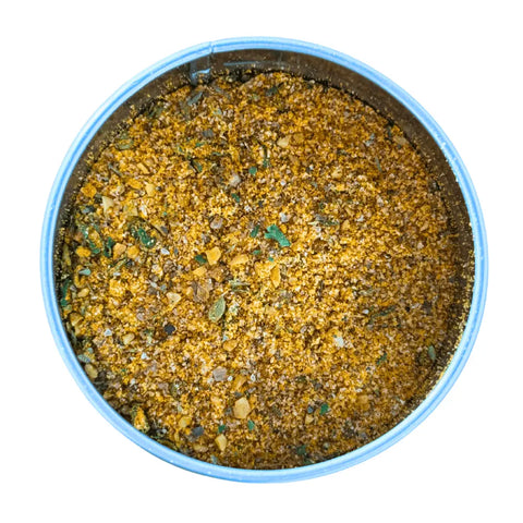 A round metal tin of Gustus Vitae’s Kid’s Menu: Butter: And House Favorite Spices, filled with a gourmet blend of coarse, golden-brown all natural herbs and seasonings, viewed from above on a white background.