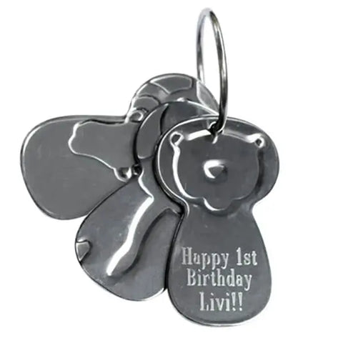 The Kleynimals – Clean Key Animals® by Kleynimals is a metal keychain with overlapping, bone and bear-shaped stainless steel tags, one engraved with Happy 1st Birthday Livi!! in a playful font.