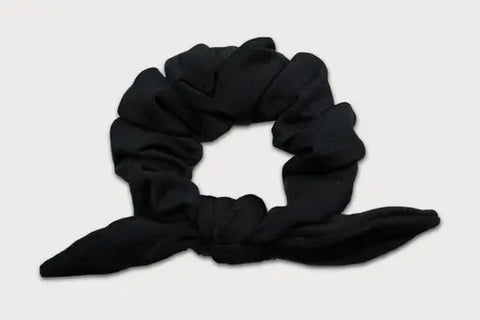 A black Knotted Bow Scrunchie by Goodnighties, crafted from thermoregulating fabric in the USA, is shown on a plain light background—an elegant hair accessory.