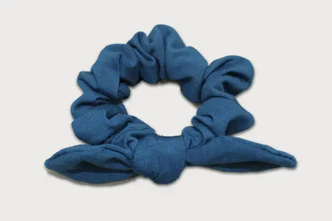 The Knotted Bow Scrunchie by Goodnighties is an American-made hair accessory crafted from blue thermoregulating fabric, featuring a cute bow and shown on a plain white background.
