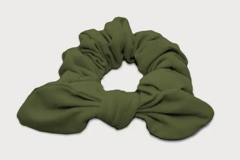 The Goodnighties Knotted Bow Scrunchie in green, made from thermoregulating fabric, is an American-made hair accessory that blends comfort and style. Shown on a white background.